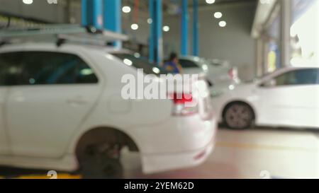 Officina di riparazione di automobili con meccanici che lavorano su più auto, concentrati Foto Stock