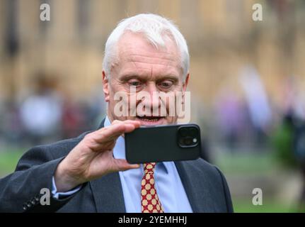 Graham Stuart MP (con: Beverley and Holderness) su College Green, Westminster, filmando la sua risposta al bilancio del governo laburista sul suo mobi Foto Stock