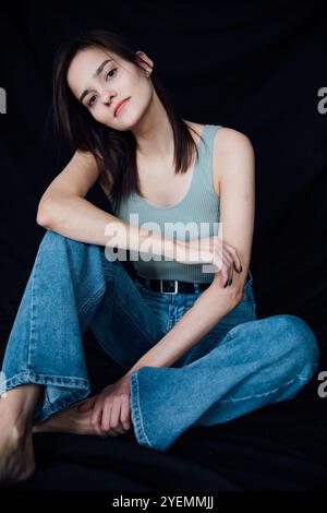 Ritratto della bella donna snella in Jeans su sfondo nero Foto Stock