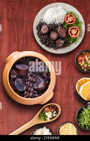 Tradizionale feijoada brasiliana con sfondo rosso. Foto Stock