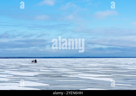 Una splendida scena invernale con un lago ghiacciato e un giro in slitta trainata da cavalli in lontananza Foto Stock