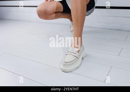 Belle gambe femminili in mocassini in pelle bianca. Scarpe estive da donna Foto Stock