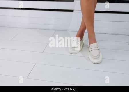 Belle gambe femminili in mocassini in pelle bianca. Scarpe estive da donna Foto Stock