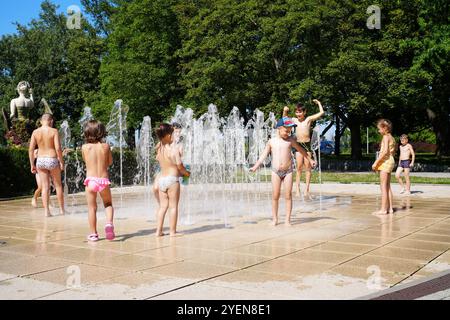 Luglio 2023. Varsavia, Polonia. Bambini felici che giocano nella fontana della città nelle calde giornate estive. Raffreddamento nei getti d'acqua. Foto Stock