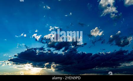 Un'incredibile esposizione di colori riempie il cielo mentre il sole tramonta, proiettando ombre sulle nuvole e creando un'atmosfera tranquilla durante le ore serali. Foto Stock