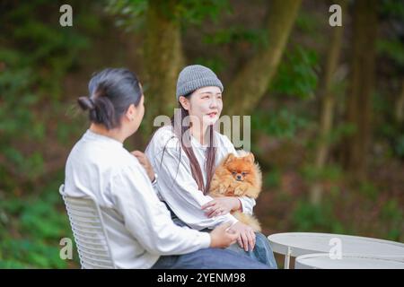 Un uomo coreano e una donna giapponese, entrambi di 30 anni e una coppia sposata, stanno godendo un brunch autunnale con tre cani in un elegante caffè situato in Foto Stock