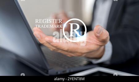 Concetto di protezione del copyright. Registrazione o registrazione del marchio. Uomo d'affari che detiene il marchio e il logo del registro su schermo virtuale. Foto Stock