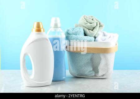 Detersivo per bucato in bottiglie e asciugamani su un tavolo in marmo grigio su sfondo azzurro Foto Stock