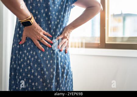 Donna con le mani dietro la schiena a causa del dolore che ha dal lumbago e dal posturale. Foto Stock