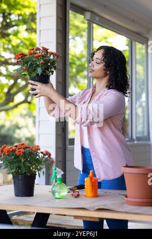 Donna che cura i fiori sul portico, godendo del giardinaggio con piante vivaci. natura, hobby, stile di vita, all'aperto Foto Stock