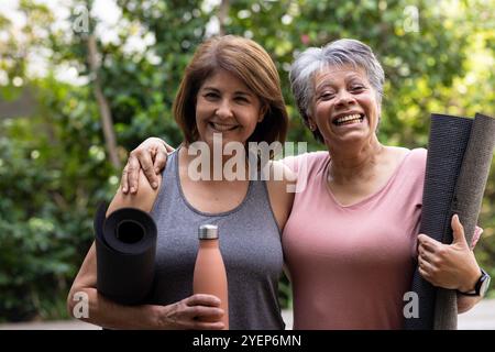 Con stuoie da yoga e bottiglia d'acqua, amiche anziane sorridenti all'aperto, amicizia. benessere, esercizio fisico, tempo libero, stile di vita Foto Stock