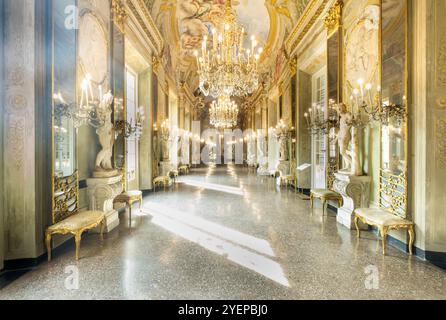 Raggi di sole illuminano la galleria di specchi con lampadari di cristallo e statue in marmo a palazzo Spinola Gambaro, Genova, Italia Foto Stock