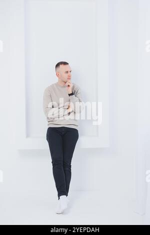 Un uomo su sfondo bianco è vestito con pantaloni raglan e neri. Abbigliamento casual da uomo. Foto Stock