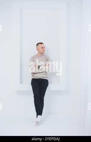 Un uomo su sfondo bianco è vestito con pantaloni raglan e neri. Abbigliamento casual da uomo. Foto Stock