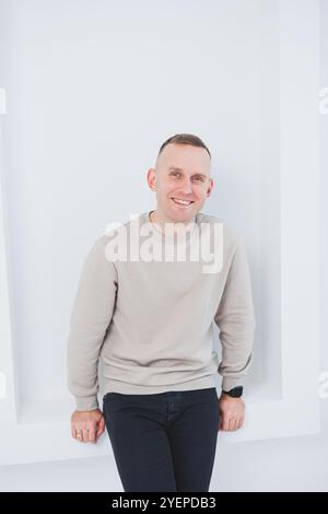 Un uomo su sfondo bianco è vestito con pantaloni raglan e neri. Abbigliamento casual da uomo. Foto Stock