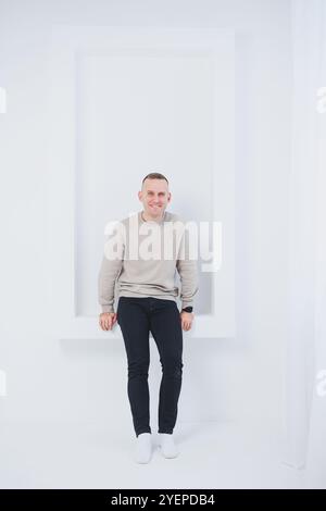 Un uomo su sfondo bianco è vestito con pantaloni raglan e neri. Abbigliamento casual da uomo. Foto Stock