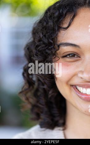 Donna sorridente all'aperto che si gode una giornata di sole, mostrando felicità e calore. sole, allegria, stile di vita, natura, libertà Foto Stock