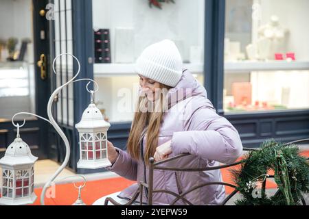 Donna sorridente in cappotto invernale con lanterna decorativa Foto Stock