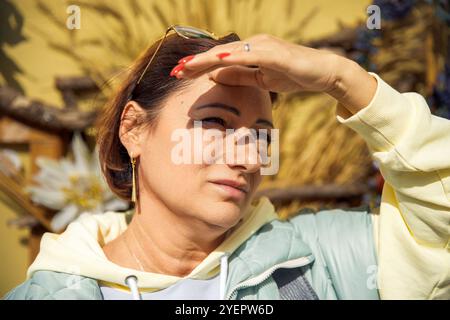 Donna che protegge gli occhi dalla luce solare Foto Stock