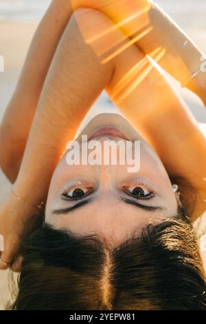 Primo piano della faccia della donna sdraiata capovolta con i lampi della luce del sole Foto Stock