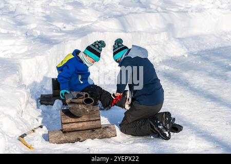 Padre aiutando son messo su pattini da ghiaccio Foto Stock