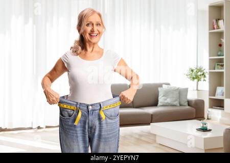 Felice donna di mezza età che prova un paio di jeans, concetto di perdita di peso Foto Stock