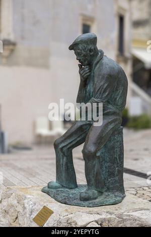 Scultura in bronzo di un uomo pensivo seduto su una pietra nel centro storico della città, Matera, Basalicata, Italia, Europa Foto Stock
