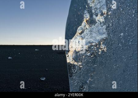 Riflessi di luce in un pezzo di iceberg incagliato dopo il tramonto, Diamond Beach, la laguna del ghiacciaio Joekulsarlon o Joekulsarlon, Islanda del Sud, Islanda, E. Foto Stock