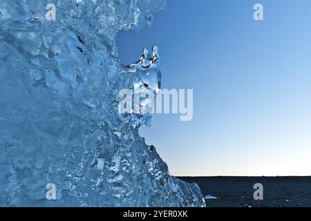 Riflessi di luce in un pezzo di iceberg incagliato dopo il tramonto, atmosfera blu, Diamond Beach, laguna del ghiacciaio Joekulsarlon o Joekulsarlon, Islanda meridionale Foto Stock