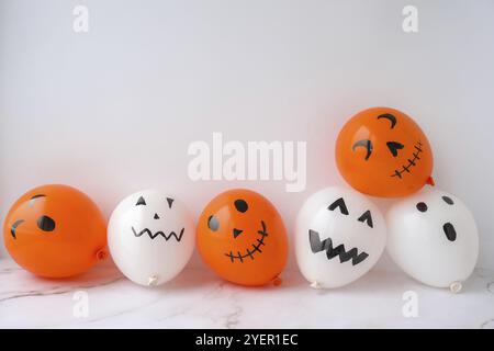 La faccia di Jack dipinta sulle bollature. Preparazione di palline bianche e arancioni fai da te per la festa di Halloween. Halloween attività a casa. Giocattoli fatti a mano Artigianato per bambini Foto Stock