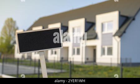 Blank cartellone nero contro casa di famiglia appartamento modello mockup vuoto etichetta Blackboard a Townhome. Copia banner spazio per il testo. Multi-famiglia Foto Stock