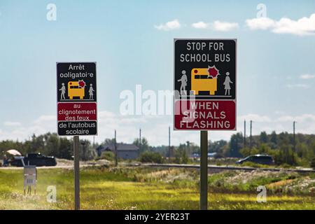 Francese e Inglese avviso due cartelli stradali sul ciglio della strada, stop per bus di scuola quando i segnali lampeggianti, Canadian strade rurali Foto Stock