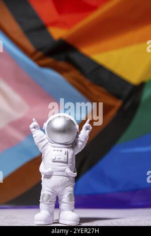 Astronauta giocattolo su bandiera Rainbow LGBTQIA in materiale di seta di fondo. Buon mese di orgoglio. Simbolo del mese di orgoglio di LGBTQ. Parità di diritti. Pace e libertà Foto Stock