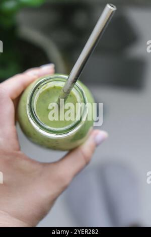 Giovane donna bionda millenaria bevendo frullato vegano bevanda detox. Donna che fa esercizi di yoga a casa. Mangiare pulito, perdita di peso, cibo sano dieta c Foto Stock