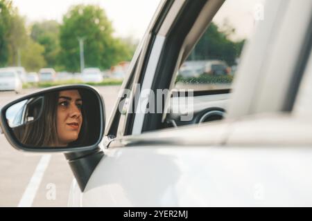 Giovane felice millennial bruna donna guida auto. Giovane donna attraente in auto. Donna guida un auto. Primo piano ritratto di bella donna outdoo Foto Stock