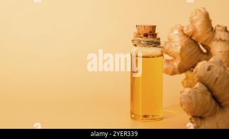 Bottiglia di vetro di olio essenziale di zenzero, radice di zenzero su sfondo beige. Concetto di cibo sano. Olio essenziale Zingiber officinale. Toni di terra Nat Foto Stock