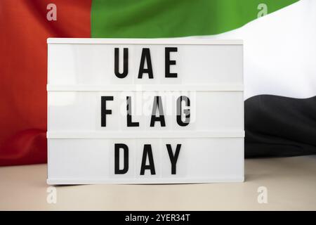 Scatola luminosa con testo BANDIERA degli Emirati Arabi Uniti, bandiera ondulata degli Emirati Arabi Uniti, realizzata in materiale di seta. Giorno della commemorazione dell'indipendenza cele festivo musulmano Foto Stock