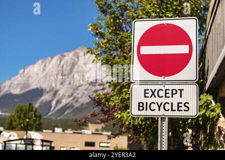 Attenzione selettiva: Non entrare nel cartello stradale con tranne il cartello per le biciclette, contro edifici e montagne e il cielo blu, British Columbia, Canada, Nord Foto Stock