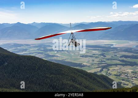 Colpo lungo di deltaplano estremo volante. Giovane che si diverte a vivere il suo viaggio ricreativo a Creston, British Columbia, Canada, Nord America Foto Stock