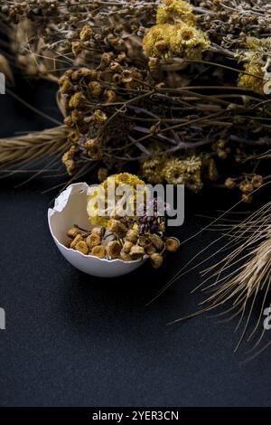 Fai da te di Pasqua. Fai da te. Decorazioni pasquali alla moda. Uova biologiche cracked con erba secca e fiori secchi su piatto. Piuma d'uccello. Spazio di copia. Greetin Foto Stock