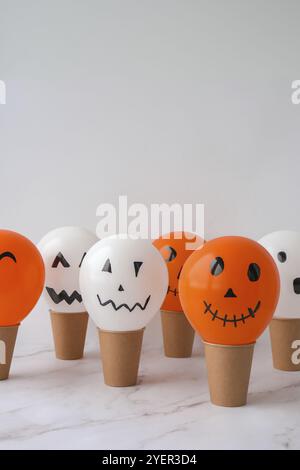 La faccia di Jack dipinta sulle bollature. Preparazione di palline bianche e arancioni fai da te per la festa di Halloween. Halloween attività a casa. Giocattoli fatti a mano Artigianato per bambini Foto Stock