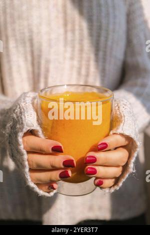 Donna irriconoscibile che tiene Pumpkin smoothie speziato latte. Caffè autunnale con aroma di zucca piccante bevanda calda di stagione. Bevande autunnali per Halloween e. Foto Stock