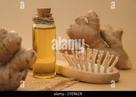 Bottiglia di vetro di olio essenziale di zenzero, radice di zenzero su sfondo beige. Vita alternativa sana. Cosmetici naturali ingredienti per la cura dei capelli. Terra Foto Stock