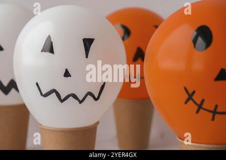 La faccia di Jack dipinta sulle bollature. Preparazione di palline bianche e arancioni fai da te per la festa di Halloween. Halloween attività a casa. Giocattoli fatti a mano Artigianato per bambini Foto Stock