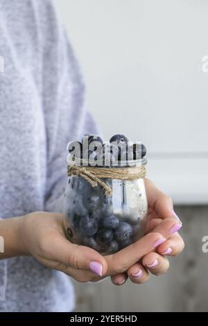 Donna che tiene ciotola con frutti di mirtillo congelati. Concetto di mietitura. Mani femminili raccogliendo bacche. Concetto di cibo sano. Stoccaggio di bacche per Foto Stock