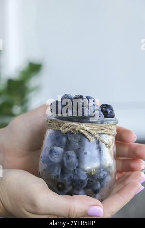 Donna che tiene ciotola con frutti di mirtillo congelati. Concetto di mietitura. Mani femminili raccogliendo bacche. Concetto di cibo sano. Stoccaggio di bacche per Foto Stock