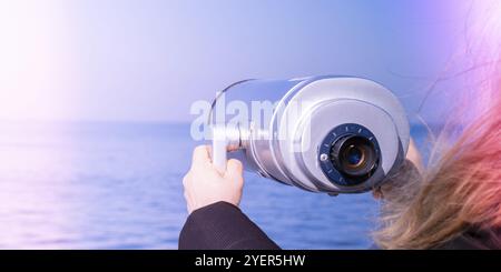 Turisti che guardano attraverso binocoli a gettoni. Telescopio binoculare sulla piattaforma di osservazione per il turismo. Sfondo marino. Binocoli che guardano a hori Foto Stock