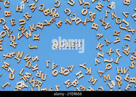 Parola TRANQUILLA fatta di lettere di legno su sfondo blu chiaro. Concetto di citazioni di parole motivazionali. Frase di ispirazione Foto Stock