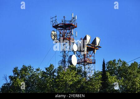 Un basso angolo di visione di un sito di cella tower alloggiata su un cavo alloggiato in acciaio pilone a traliccio, antenna a microonde per 3G, 4G, 5G il trasferimento dei dati e il segnale boost Foto Stock