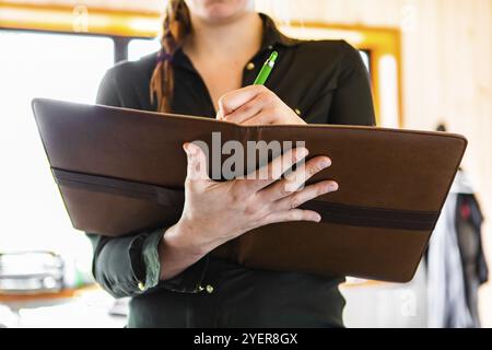 Messa a fuoco selettiva e vista ravvicinata di una clipboard sulle mani di una donna irriconoscibile mentre prende appunti. ispettore edile donna al lavoro Foto Stock